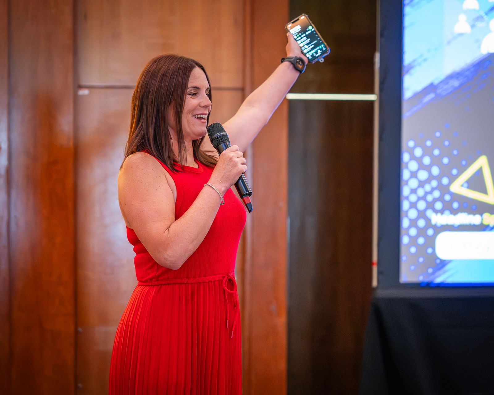 Speaker in red addressing the room at a conference
