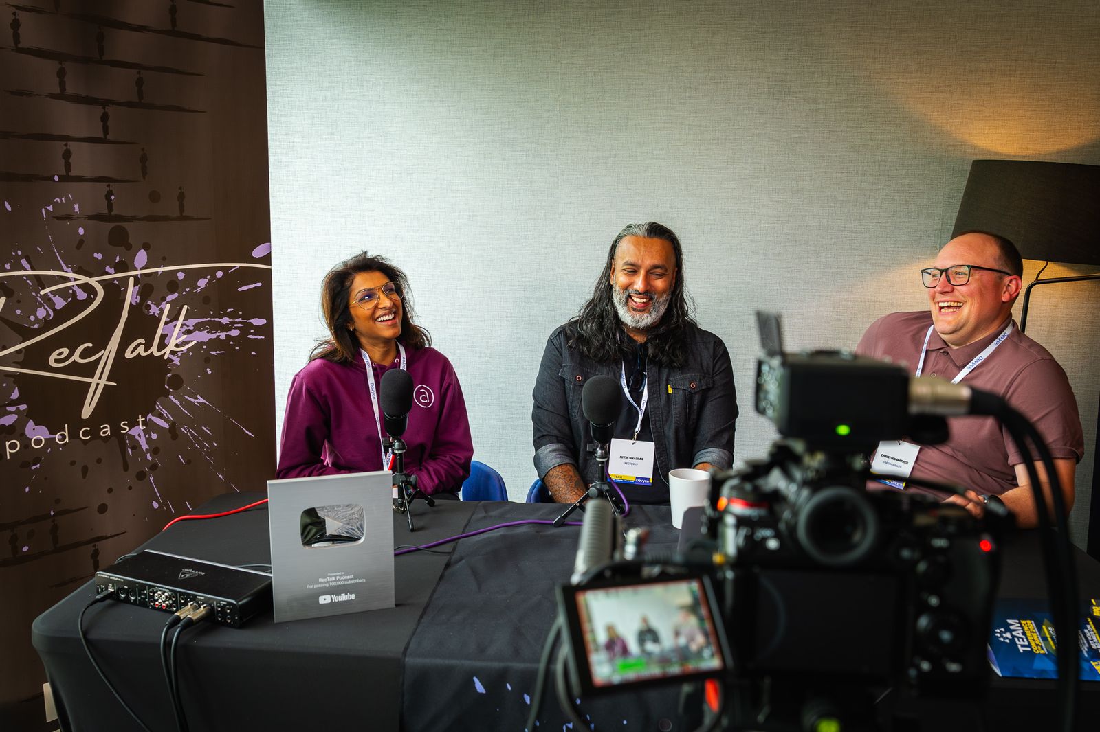 Behind the scenes at a live podcast recording, camera in the foreground